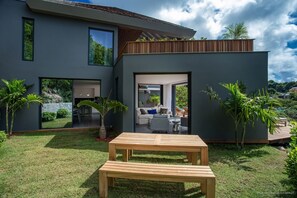 A modern house with a patio, large windows, and a view of the surrounding landscape.
