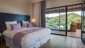 A modern bedroom with a large bed, a view of a lush green landscape, and a sliding glass door to an outdoor area. - Beautiful Sasha Luxury villa (Corossol)