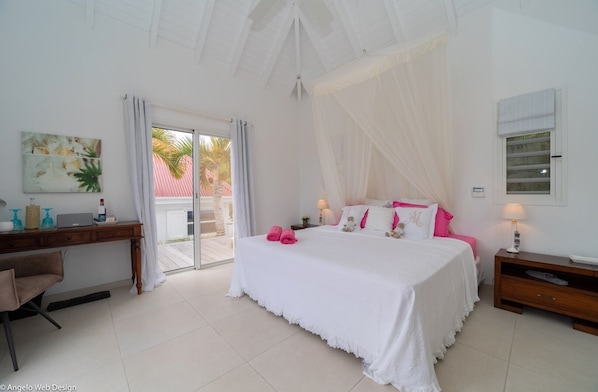 A bedroom with a bed, a desk, a chair, a nightstand, and a window.