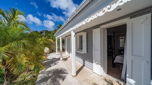 Uma casa com varanda coberta, portas abertas e vista para o verde ao redor.