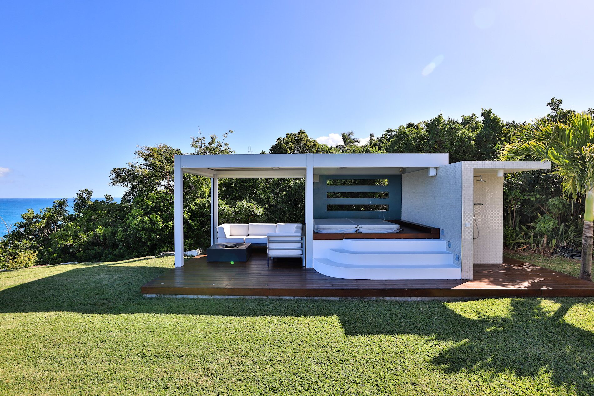 Un espacio exterior moderno con cama integrada, zona de estar y ducha.