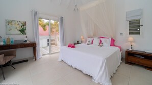 A bedroom with a bed, a desk, a chair, a nightstand, and a window. - Beautiful Minou Luxury villa (Grand Cul de Sac)
