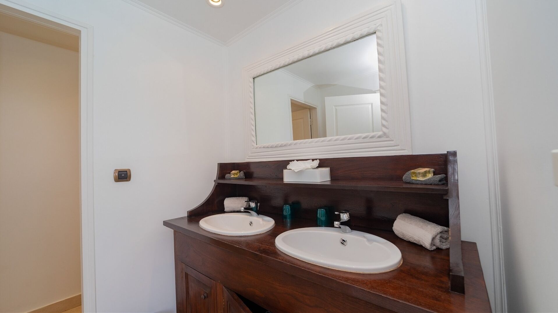A bathroom with two sinks, a mirror, and a towel rack.