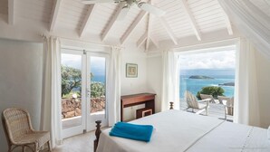 Ein Schlafzimmer mit Bett, Stuhl, Schreibtisch und Meerblick.