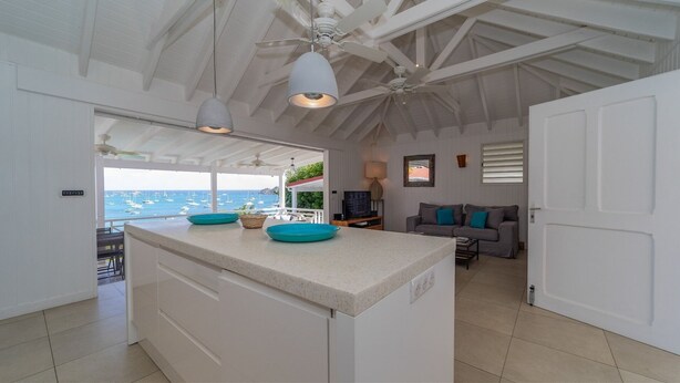 Eine geräumige Küche mit einer großen Kochinsel, ein Essbereich mit einer Couch und Blick auf das Meer.