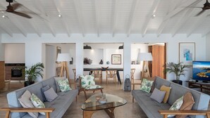 Ein großzügiger Wohnraum mit zwei Sofas, einem Glastisch und einem Essbereich mit Holztisch und Stühlen.