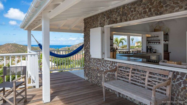 A covered outdoor area with a stone wall, wooden deck, a hammock, and a view of the ocean. - Supersky (2/3 Rooms) Luxury villa (St barts)