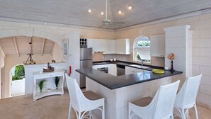 A modern kitchen with white cabinetry, a central island, and a ceiling fan.