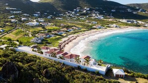 Eine Luftaufnahme einer Küstenwohngegend mit Häusern, einem Strand und einem Berg im Hintergrund.