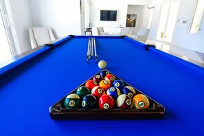 A pool table with balls arranged in a triangle, a cue stick, and a billiard ball in the air.