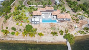 An aerial view of a resort with a swimming pool, multiple buildings, and surrounding palm trees. - Mirabelle (3/5 Rooms) (Terres Basses)