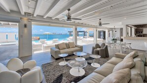 A spacious living area with a view of the sea, a pool, and a modern kitchen. - Mirabelle (3/5 Rooms) (Terres Basses)