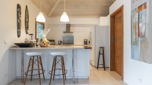 Una cocina moderna con una isla central, luces colgantes y taburetes de bar.