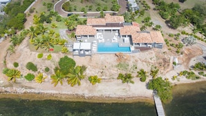 An aerial view of a resort with a swimming pool, multiple buildings, and surrounding palm trees. - Mirabelle (4/5 Rooms) (Terres Basses)