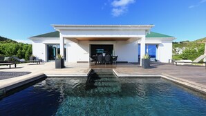 Ein modernes Haus mit Swimmingpool, Sitzgelegenheiten im Freien und Blick auf die umliegende Landschaft.