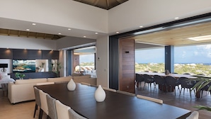 Un interior moderno con comedor, sofá y un amplio ventanal que ofrece vistas del paisaje.