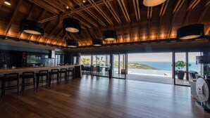 A spacious kitchen with a bar area, large windows offering a view of the ocean, and a wooden ceiling with hanging lights. - Jade (4/8 Rooms) Luxury villa (Marigot)