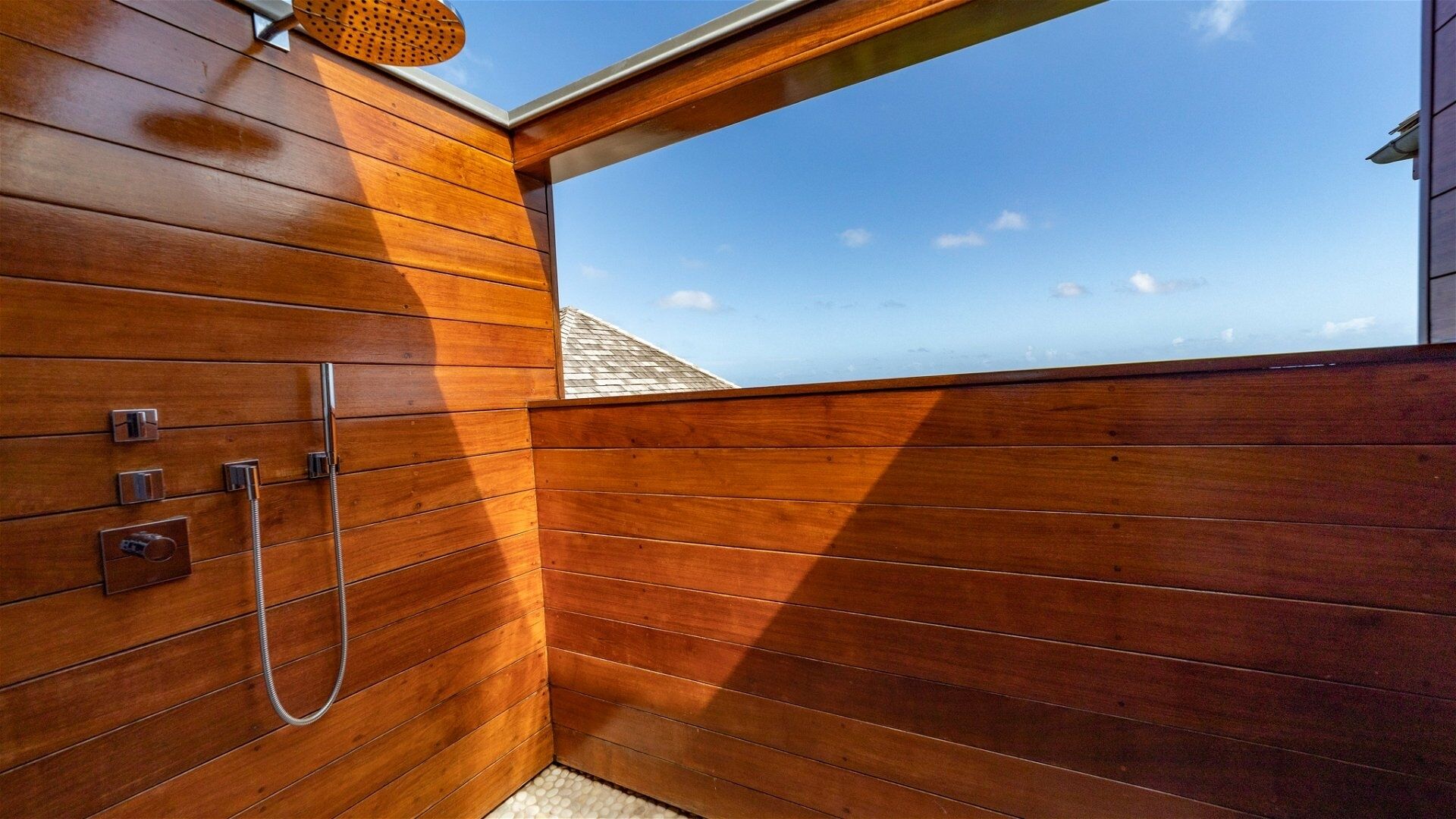 Une salle de bain en bois avec une lucarne, une douche et une vue sur le ciel.