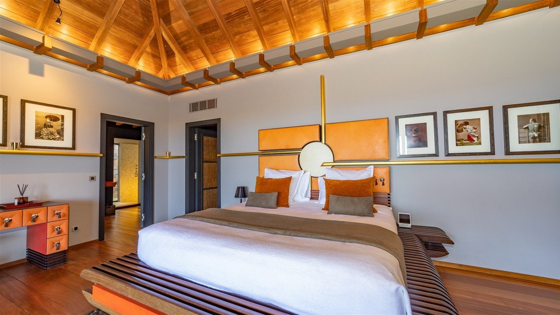 Una habitación de hotel moderna con una cama grande, vigas de madera en el techo y obras de arte enmarcadas en las paredes.