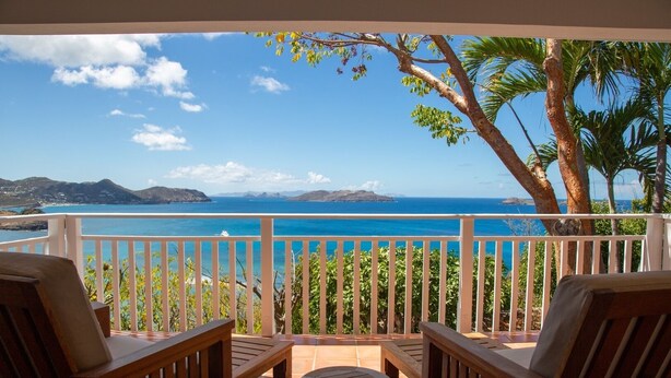 A balcony with wooden furniture and a view of the ocean. - Sucrier (1/2 Rooms) Luxury villa (Lorient)