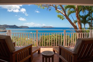 A balcony with wooden furniture and a view of the ocean. - Sucrier (1/2 Rooms) Luxury villa (Lorient)