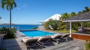 A poolside area with lounge chairs, a wooden deck, and a view of the ocean. - Sucrier (1/2 Rooms) Luxury villa (Lorient)