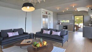 A modern living room with two grey sofas, a coffee table with fruit, and a kitchen in the background. - Eranos (1/2 Rooms) Luxury villa (St. Barts)