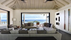 Ein geräumiges Wohnzimmer mit einer großen Couch, einem Couchtisch und Blick auf den Ozean.