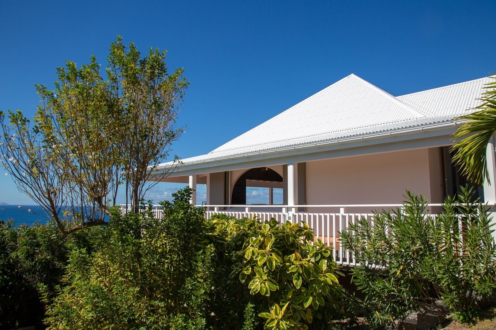 A coastal house with a white roof, a covered porch, and a view of the ocean.