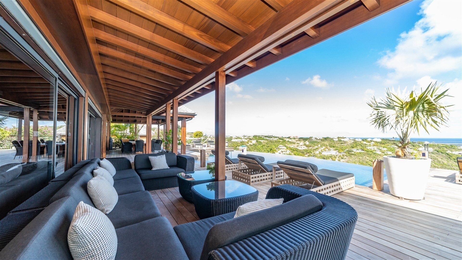 A covered outdoor seating area with a view of the ocean and a distant landscape.