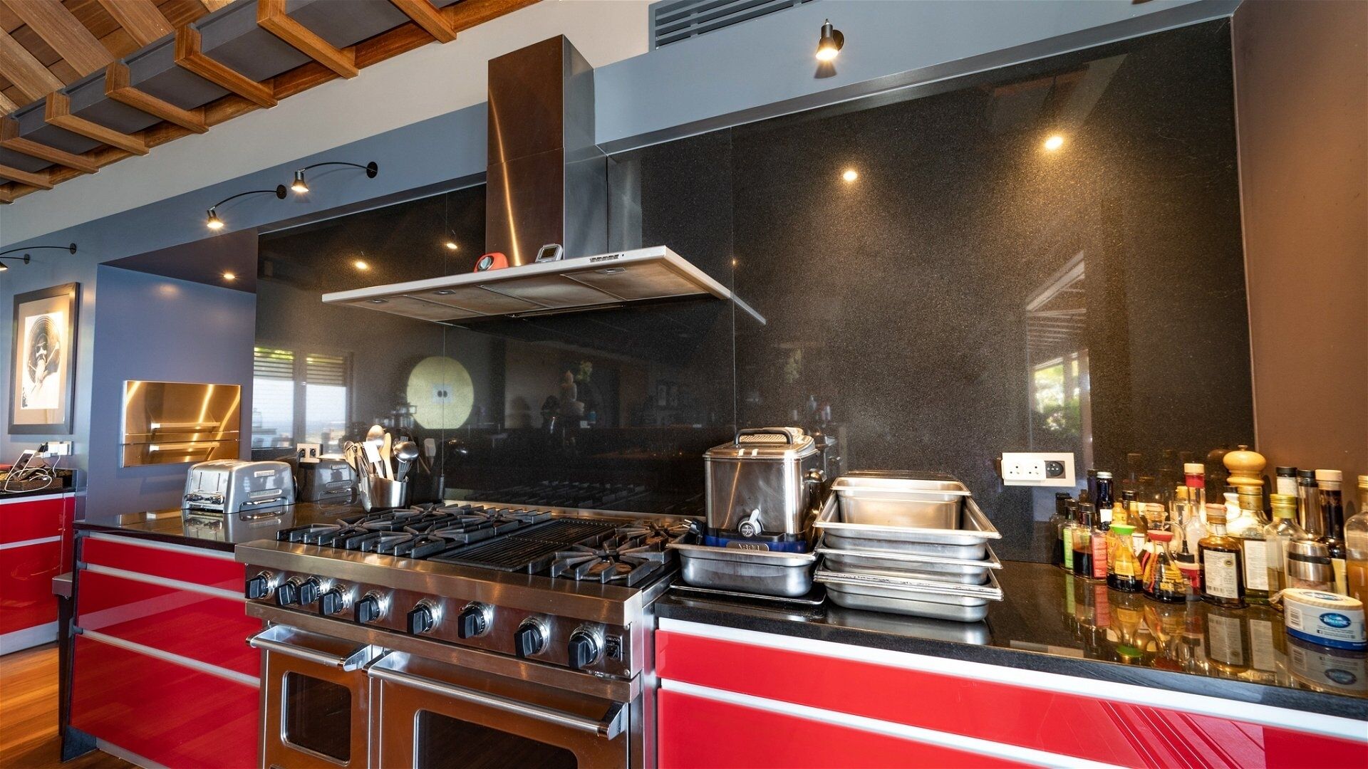 A modern kitchen with a stainless steel stove, a large range hood, and a countertop with various kitchen appliances and utensils.
