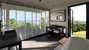 Une salle de bain moderne avec une grande fenêtre, un lavabo, un miroir et une baignoire.