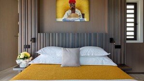 Moderni hotellihuone, jossa on suuri sänky, seinälle ripustettu taulu ja ikkuna, jossa on sälekaihtimet.
