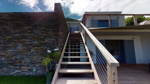 Una escala moderna que mena a un edifici residencial amb un mur de pedra i una porta de vidre.