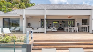 A modern house with a covered outdoor area, including a dining space and seating.