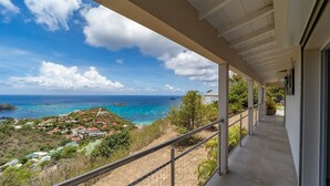 Ein Balkon mit Blick auf das Meer, Gebäude und Grünflächen.