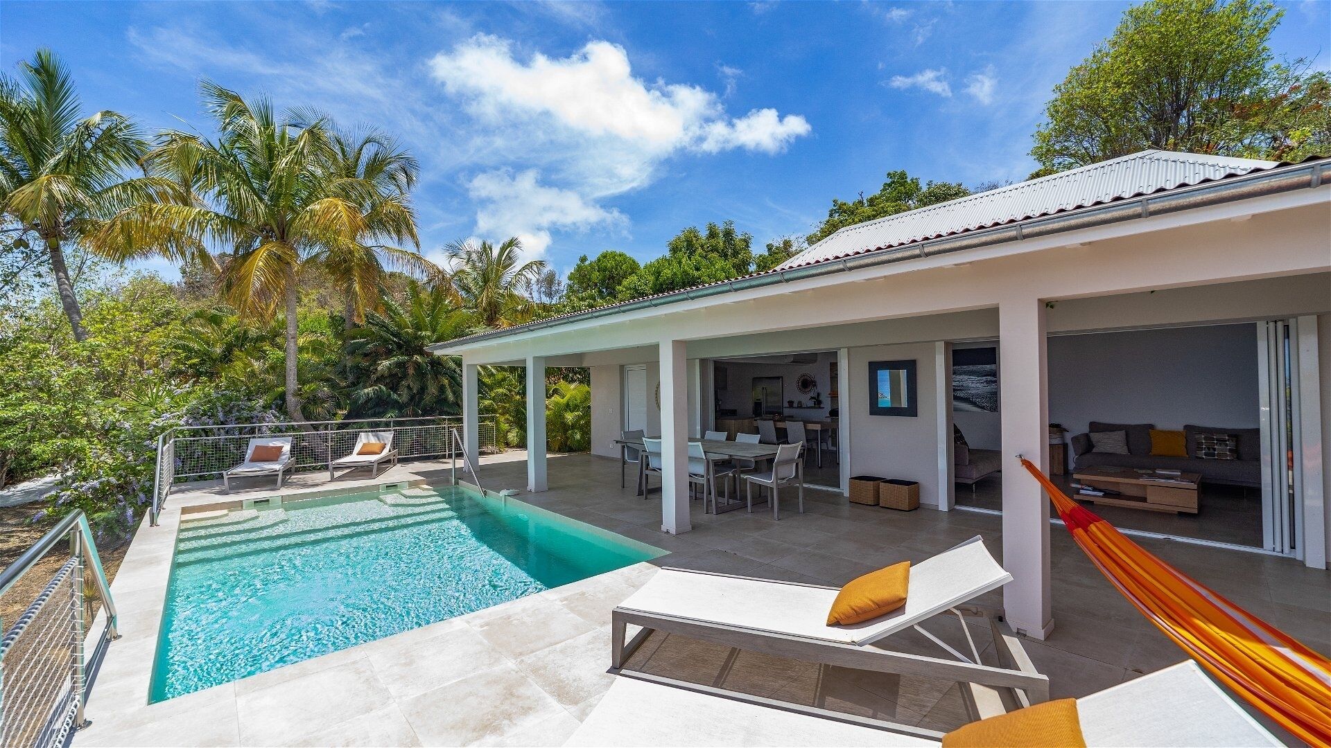 A modern house with a swimming pool, outdoor seating, and a covered patio area.