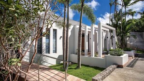 A modern building with white walls and large windows, surrounded by palm trees and a well-maintained lawn. - Bastide (2/3 Rooms) Luxury villa (St Barts)