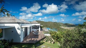 A modern house with a large deck, a swimming pool, and a view of the ocean and hills. - Bastide (2/3 Rooms) Luxury villa (St Barts)
