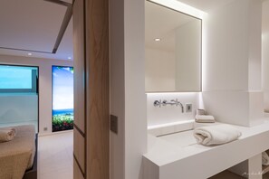A modern bathroom with a large mirror, a white sink, and a towel on the counter.