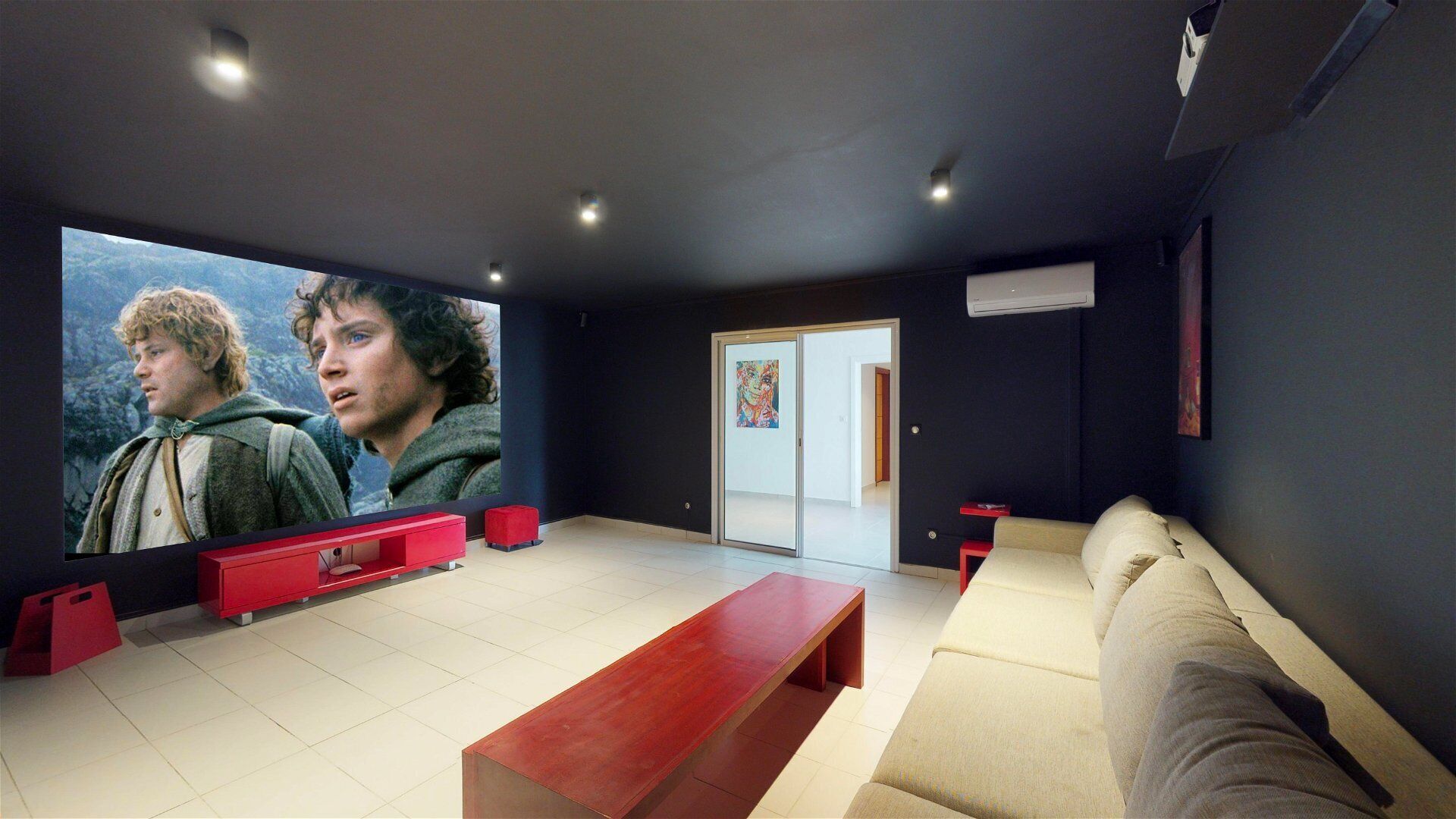 A modern home theater room with a large flat-screen TV, a red bench, and a beige couch.