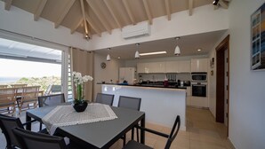 Una cucina moderna con mobili bianchi, un'isola centrale e un'area pranzo con tavolo e sedie.