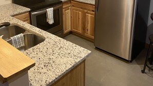 A kitchen with wooden cabinets, stainless steel appliances, granite countertops, and a sign that says "Show grace". - The Blue Door Cabin  (Winston-Salem)