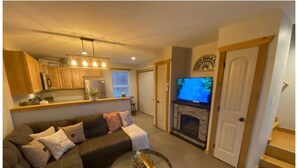 A living room with a sectional sofa, a glass coffee table, and a fireplace. - The Blue Door Cabin  (Winston-Salem)