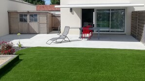 Ett modernt hus med en uteplats, en skjutdörr i glas och en liten trädgårdsyta.