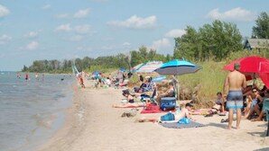 Une plage où l’on peut voir des gens bronzer et se baigner, avec des parasols et des chaises de plage.