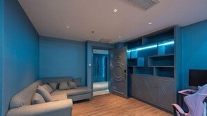 Een moderne kamer met een grijze bank, een roze fauteuil en een in de muur ingebouwde entertainmentkast met planken.