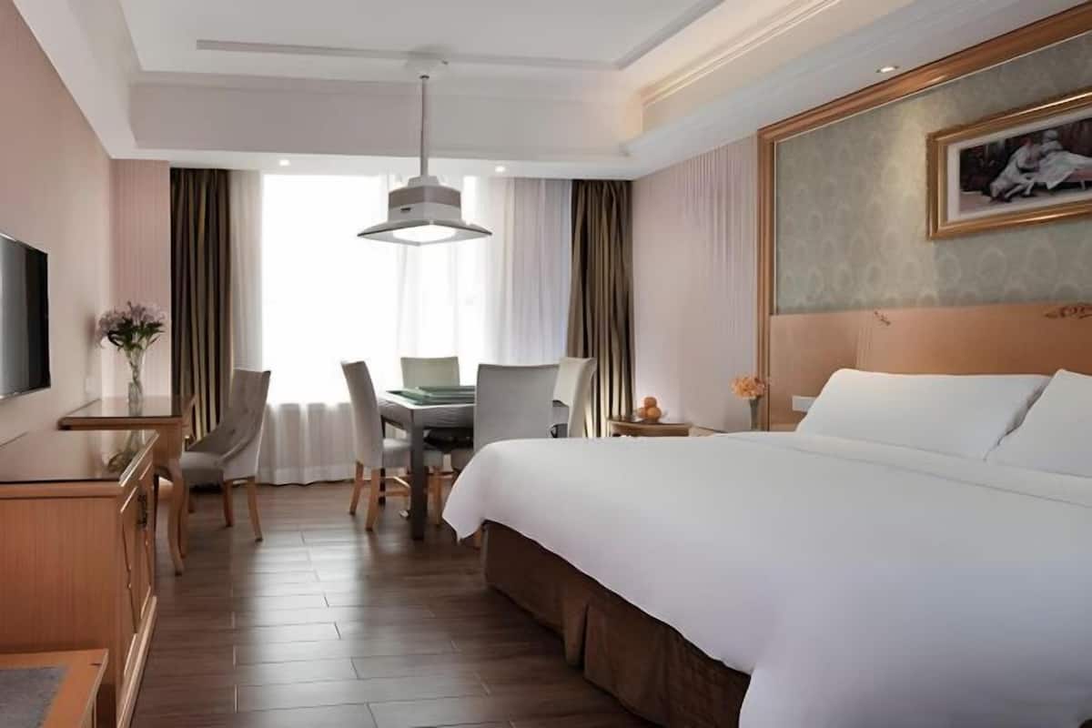 A hotel room with a bed, desk, chair, and a television.