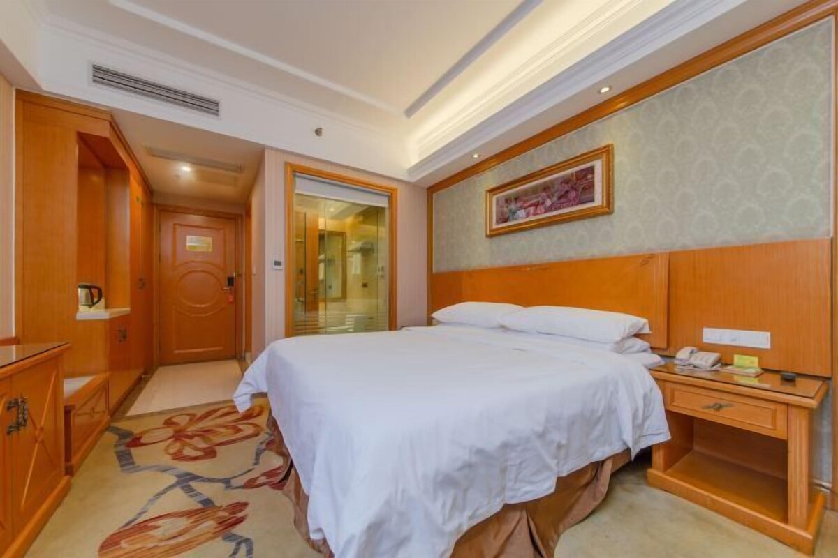 A hotel room with a bed, bedside table, and a wardrobe.