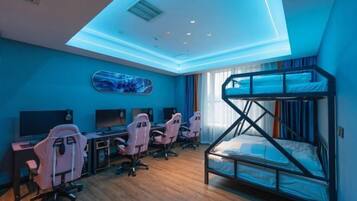 A room with a bunk bed, a desk with computers, and a large window.